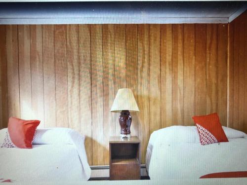 a room with two beds and a lamp on a table at Monmouth OYO in Neptune City
