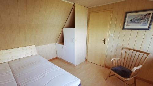 a small bedroom with a white bed and a chair at Ferienhaus SeeWaldMeer am Pinnower See bei Schwerin in Pinnow