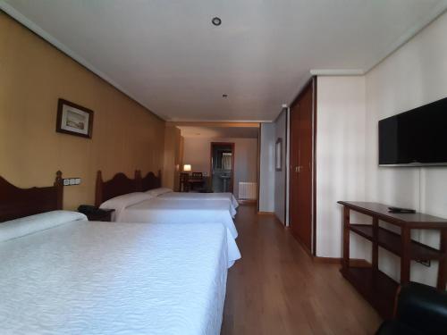 a hotel room with two beds and a flat screen tv at Favila Oviedo in Oviedo