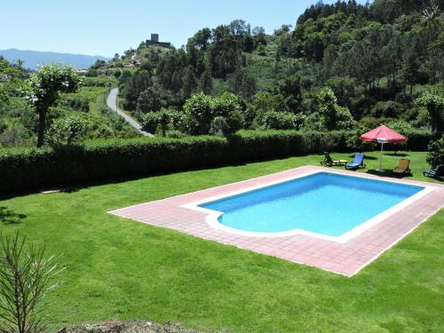 a swimming pool in a yard with a grassy yard at Casa das Vessadas in Celorico de Basto