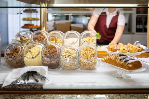 eine Theke mit vielen Behältern mit Lebensmitteln und Gebäck in der Unterkunft Hotel Desiree in Lignano Sabbiadoro