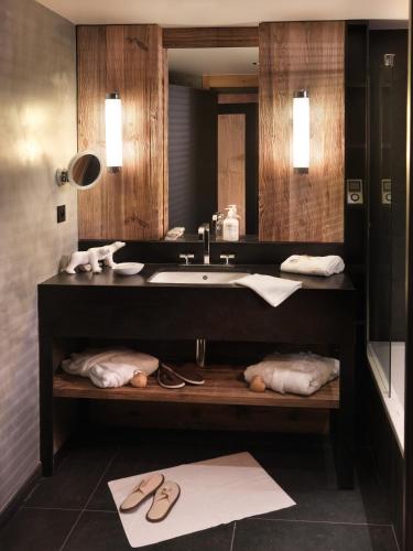 a bathroom with a sink and a mirror and towels at M de Megève in Megève