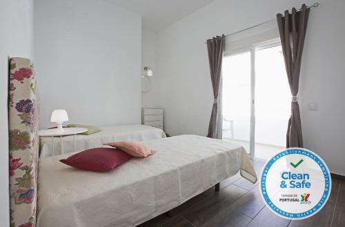 un dormitorio con 2 camas y un cartel que diga limpio y seguro en DownTown Albufeira beach Apartment, en Albufeira