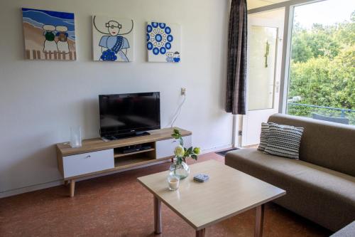 a living room with a couch and a tv at Vakantiehuisje Martina 24 in Vlissingen