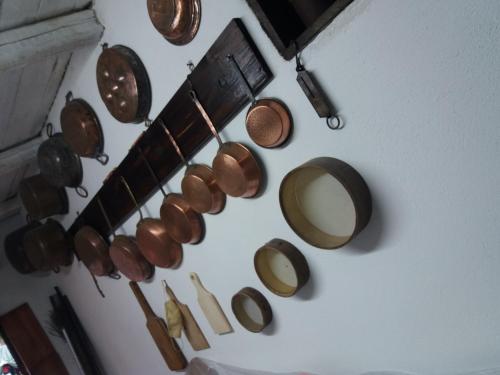 a bunch of copper pots and pans hanging on a wall at Belli come il Sole in Serri