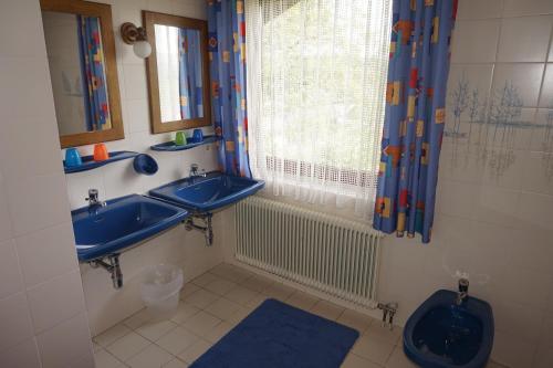 uma casa de banho com 2 lavatórios, um WC e uma janela em Gästehaus Resei em Schiefling am See
