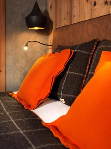 a bed with orange pillows on it with a lamp at M de Megève in Megève
