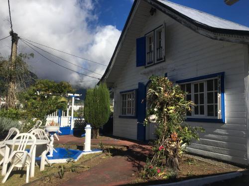 ein blau-weißes Haus mit einem Tisch und Stühlen in der Unterkunft LE CALBANON in Cilaos