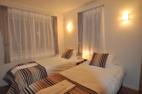 two beds in a hotel room with a window at Cat's Villa Hakuba 2- Vacation STAY 82203 in Hakuba