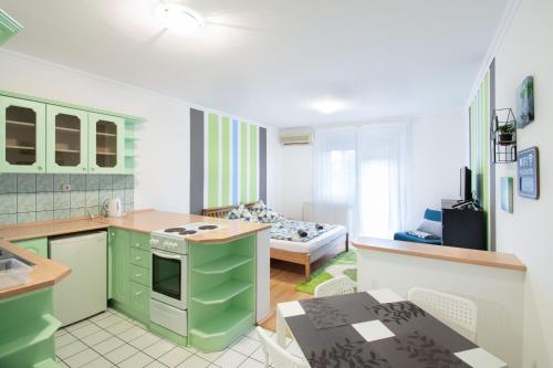a kitchen with green cabinets and a living room at Lux Apartmanok in Hajdúszoboszló