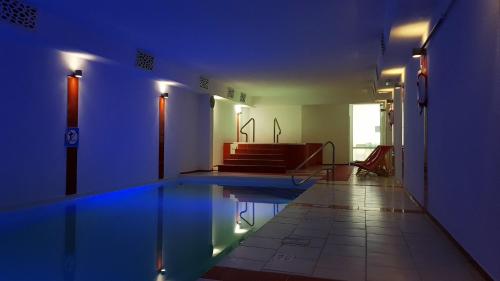 uma piscina num quarto com iluminação azul em Akwamaryn Spa Niechorze em Niechorze