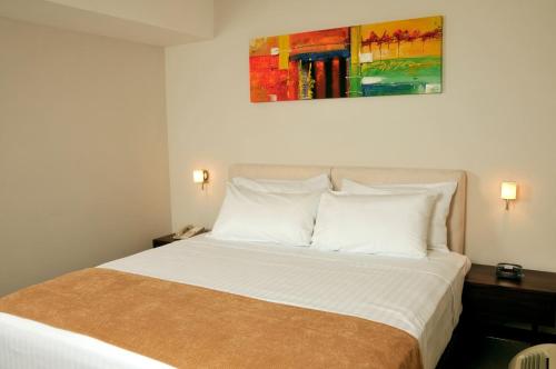 Hotel Hex Estelí في إستيلي: غرفة نوم بسرير ابيض مع لوحة فوقها