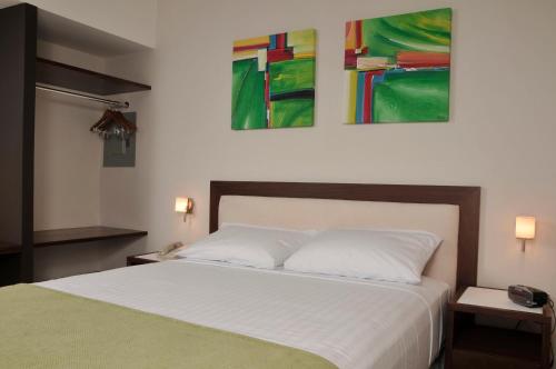 a bedroom with a bed with two paintings on the wall at Hotel Hex Estelí in Estelí