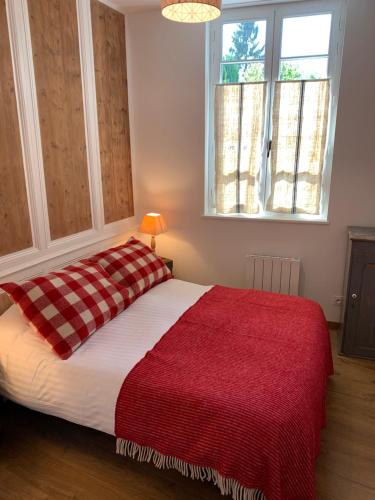 um quarto com uma cama com um cobertor vermelho e uma janela em CHEZ PAUL em Honfleur