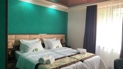 a bedroom with a large bed with a green wall at Georgia Gold in Gori