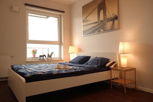 łóżko w pokoju z oknem i łóżko z niebieskimi poduszkami w obiekcie Apartament Nadwarciański w Poznaniu
