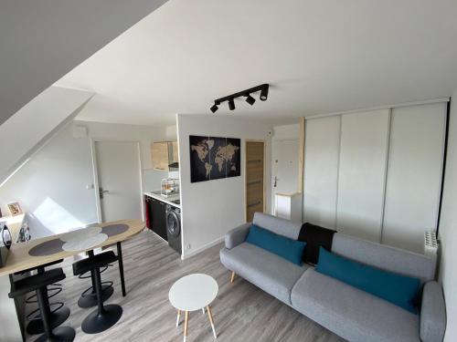 a living room with a couch and a table at Escapade à Cabourg, 300M plage, calme et chaleureux in Cabourg