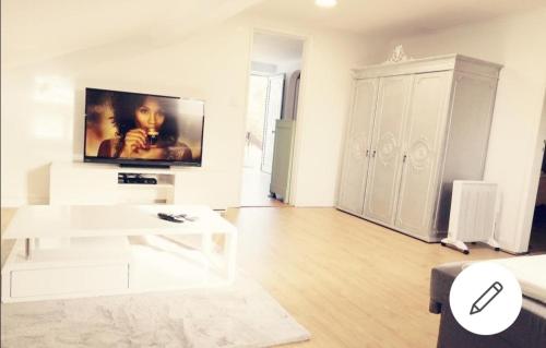a white living room with a tv on the wall at Sesimbra Beach Fonte House in Sesimbra