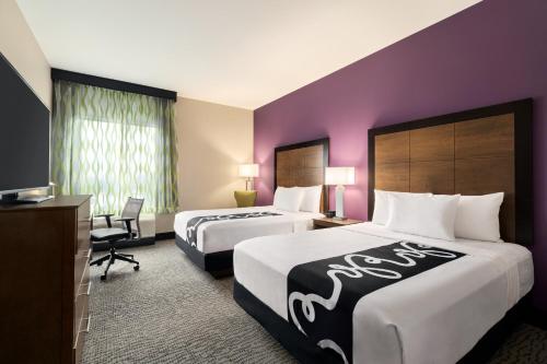 two beds in a hotel room with purple walls at La Quinta Inn & Suites by Wyndham Burlington in Burlington