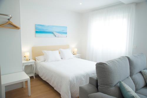 a white bedroom with a bed and a couch at L3 Loft O Grove Centro aire acondicionado parking in O Grove