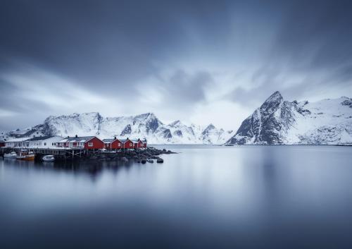 a house on a dock in the water with mountains at Eliassen Rorbuer in Reine
