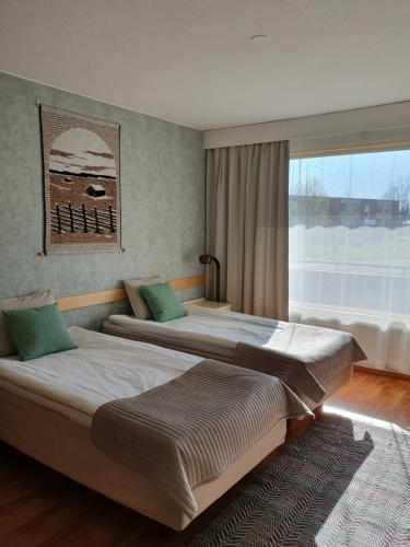 two beds in a room with a large window at Majoitus Hermanni in Teuva