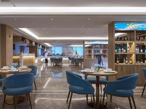 um restaurante com cadeiras e mesas azuis numa sala em Kyriad Hotel Dongguan Dalingshan South Road em Dongguan