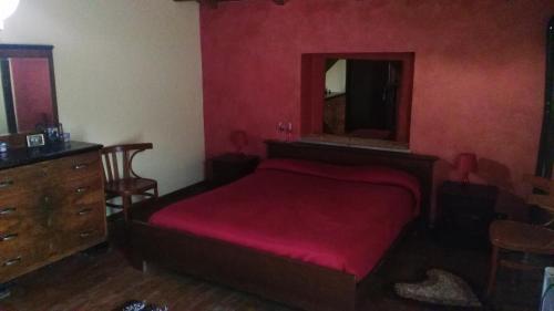 a bedroom with a red bed and a dresser and a mirror at Chalet Del Pozzo in Luco neʼ Marsi