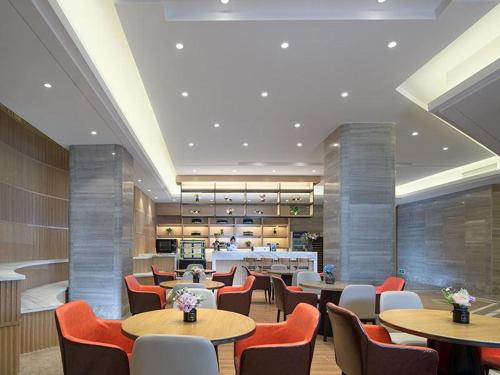 a restaurant with tables and chairs and a cafeteria at Kyriad Mavelous Hotel Shantou Gurao in Shantou