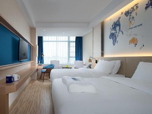 a hotel room with two beds and a flat screen tv at Kyriad Mavelous Hotel Shantou Gurao in Shantou