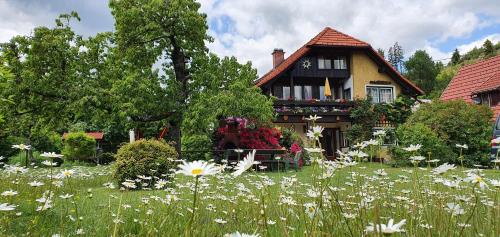 une maison avec un champ de fleurs devant elle dans l'établissement Landhaus Egger, à Seeboden
