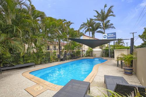 a swimming pool with chairs and palm trees at Best Western Airport 85 Motel in Brisbane