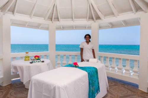 a woman standing in a room with two tables at Edgewater Beach Villa - Beach Front, Close to All Attractions in St Mary