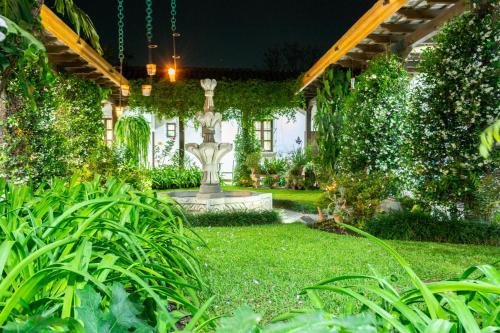 a garden at night with a statue in the yard at Hotel Las Marias in Antigua Guatemala