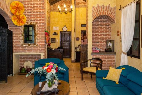a living room with two blue couches and a fireplace at Hotel Las Marias in Antigua Guatemala