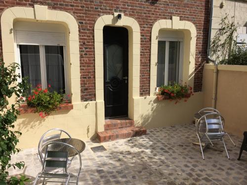 een patio met 2 stoelen en een zwarte deur bij La Villa des Remparts in Lisieux