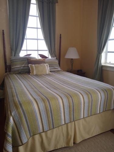 a bedroom with a large bed with a striped blanket at The Great House Inn in Belize City