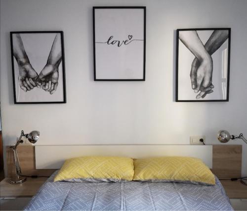 a bedroom with three pictures of two hands on the wall at Apartamento Las Huellas in Arnedillo