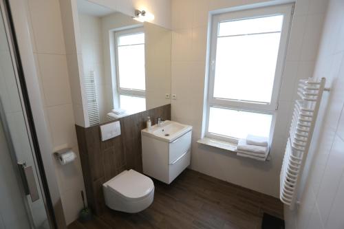 een badkamer met een toilet, een wastafel en een raam bij Apartamenty MGM Legionowo in Legionowo