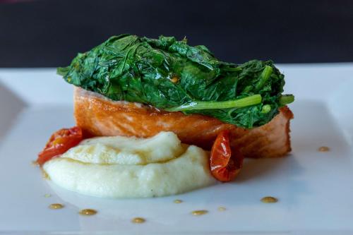 a white plate with a piece of fish with greens on it at Best Western Plus Hotel Monza e Brianza Palace in Cinisello Balsamo