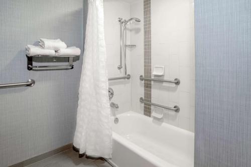 a bathroom with a tub and a shower with towels at Hyatt Place Charlotte Airport Billy Graham Parkway in Charlotte