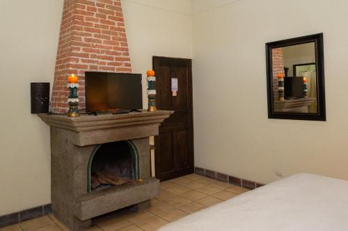 a room with a fireplace with a tv on top at Hotel Las Marias in Antigua Guatemala