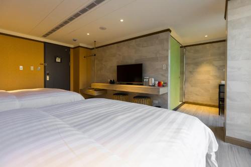 a bedroom with a large white bed and a television at Q21 Hotel in Kaohsiung