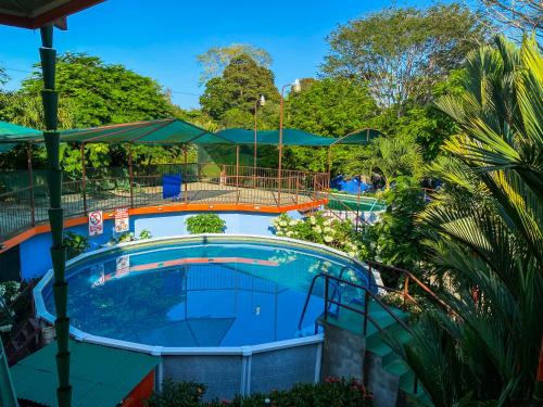 a pool at a resort with trees and bushes at Hotel Cabinas el Tecal in Uvita