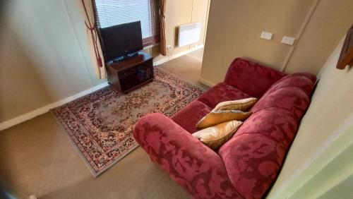 a red couch sitting in a living room at Blakes Manor Self Contained Heritage Accommodation in Deloraine