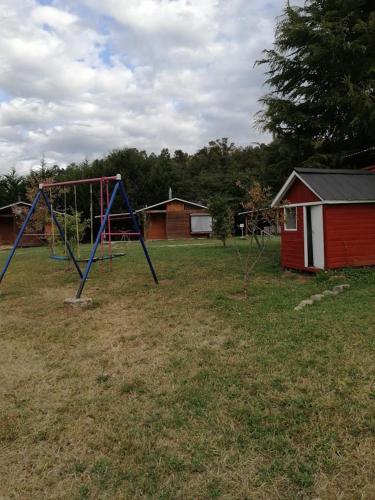 a playground with a swing set in a field at Turismo Jaos Cabañas Tinas y Quincho in Futrono
