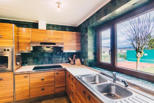 a kitchen with wooden cabinets and a sink and a window at Barandi Urbasa in Olazagutía