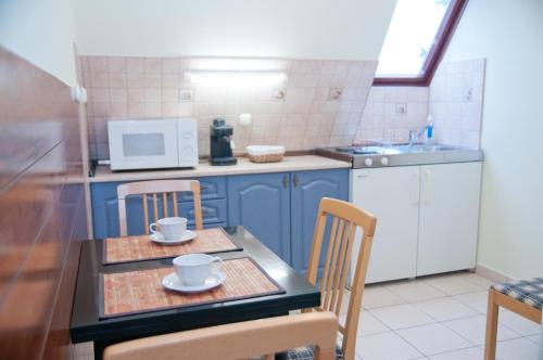 cocina con armarios azules, mesa y sillas en Apartments Yowan, en Hévíz