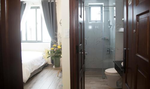 a bathroom with a shower and a toilet and a bedroom at Pontus Hotel in Da Lat