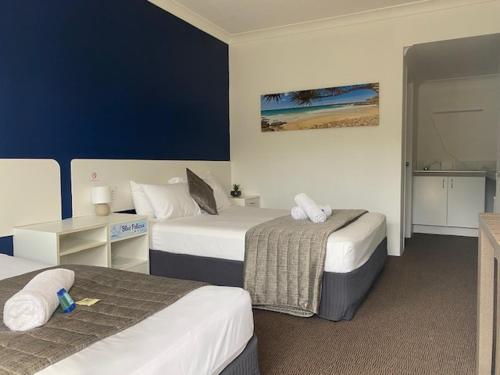 Habitación de hotel con 2 camas y mesa en Blue Pelican Motel, en Tweed Heads